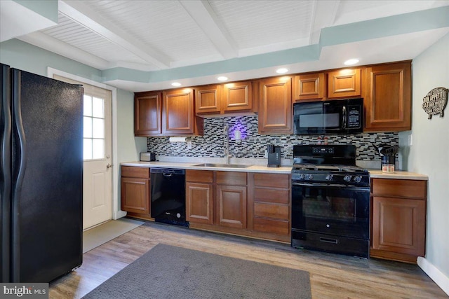 kitchen with light hardwood / wood-style flooring, black appliances, decorative backsplash, beamed ceiling, and sink