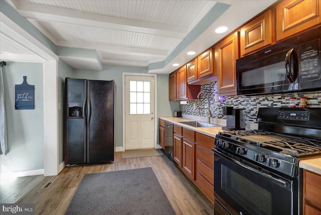 kitchen with sink, black appliances, tasteful backsplash, and light hardwood / wood-style floors