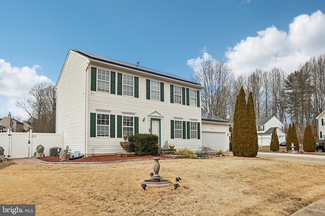 colonial house with central AC unit, a front lawn, and fence