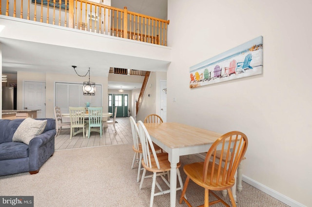 carpeted dining room with a towering ceiling