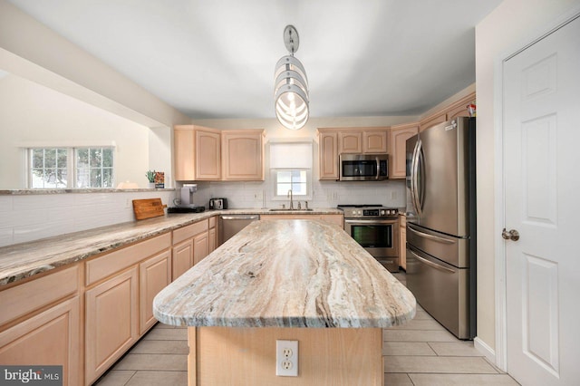 kitchen featuring sink, a center island, light brown cabinets, appliances with stainless steel finishes, and light stone countertops