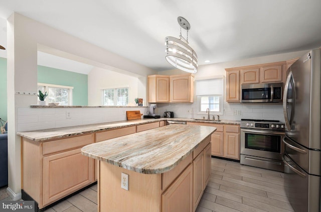 kitchen with sink, stainless steel appliances, a kitchen island, kitchen peninsula, and light brown cabinets