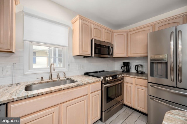 kitchen with sink, stainless steel appliances, light stone counters, tasteful backsplash, and light brown cabinetry