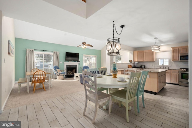 dining area featuring vaulted ceiling, ceiling fan, sink, and light wood-type flooring