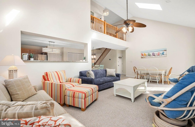 carpeted living room featuring ceiling fan, a skylight, and high vaulted ceiling