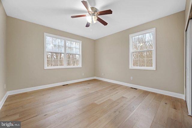 spare room with ceiling fan, a healthy amount of sunlight, and light hardwood / wood-style flooring