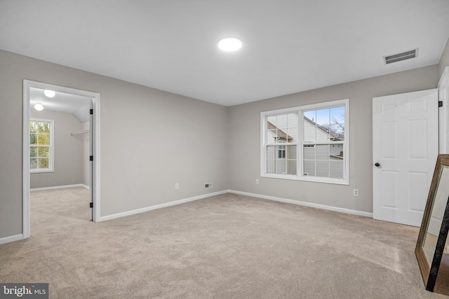 unfurnished bedroom with a spacious closet and light colored carpet