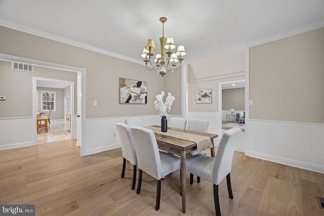 dining area featuring an inviting chandelier, crown molding, and light hardwood / wood-style flooring