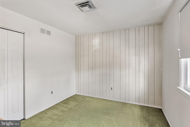 carpeted spare room with wood walls