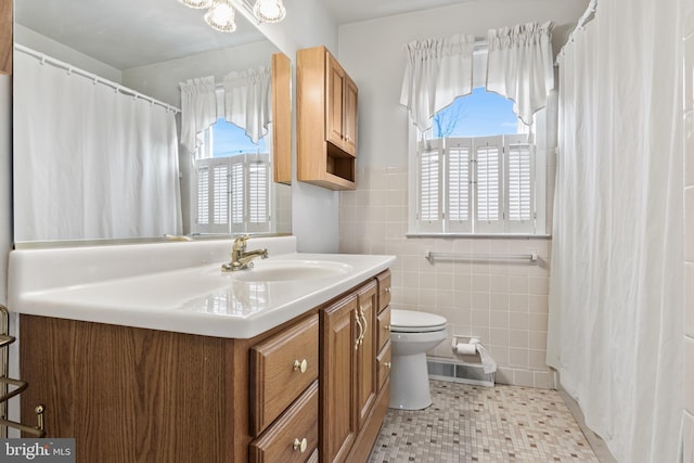 bathroom with toilet, tile walls, and vanity