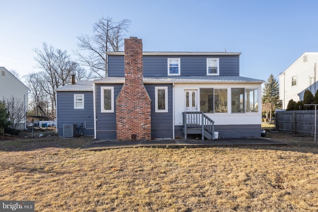 rear view of property with central AC unit, a lawn, and a sunroom