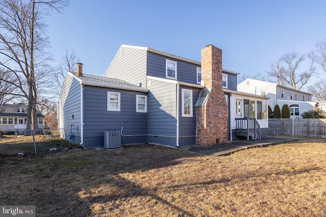 back of property with a lawn and central AC