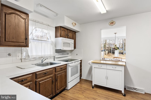 kitchen featuring light hardwood / wood-style flooring, sink, white appliances, tasteful backsplash, and pendant lighting