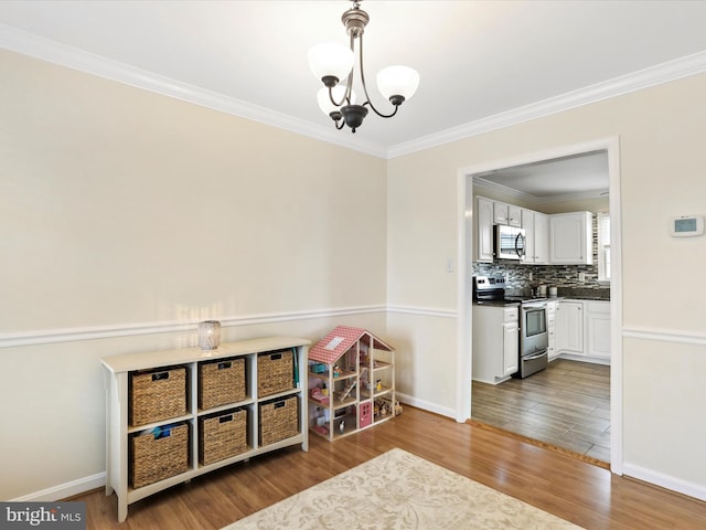 rec room featuring ornamental molding, a chandelier, and wood-type flooring