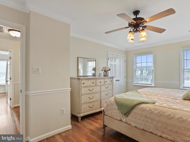 bedroom featuring light wood-type flooring, ornamental molding, ceiling fan, and a closet