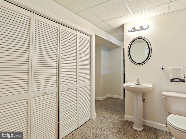 bathroom featuring sink, a drop ceiling, and toilet