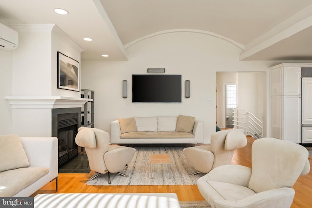 living room featuring an AC wall unit, lofted ceiling, and hardwood / wood-style flooring