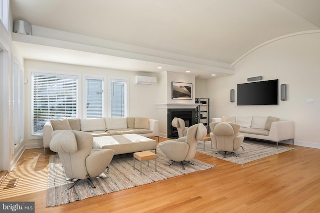 living room featuring vaulted ceiling, wood-type flooring, and a wall mounted AC