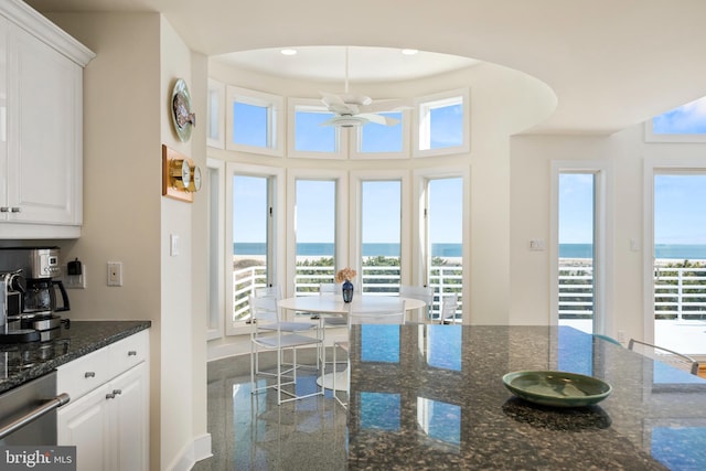 interior space featuring white cabinets, dark stone counters, and a water view