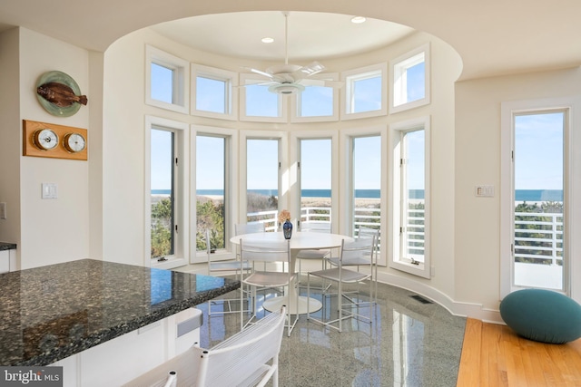 sunroom / solarium featuring a water view and ceiling fan