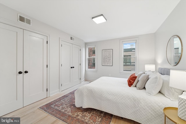 bedroom with two closets and light wood-type flooring