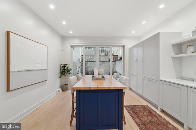 kitchen featuring a center island, a breakfast bar area, wood counters, and light hardwood / wood-style flooring