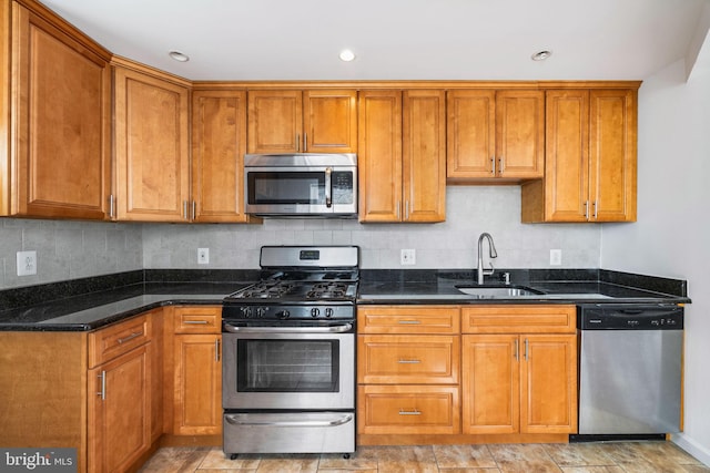 kitchen featuring stainless steel appliances, sink, decorative backsplash, and dark stone counters