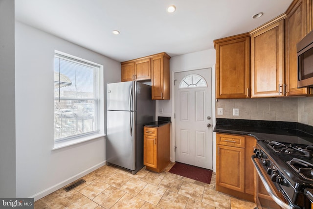 kitchen featuring tasteful backsplash, appliances with stainless steel finishes, and dark stone countertops