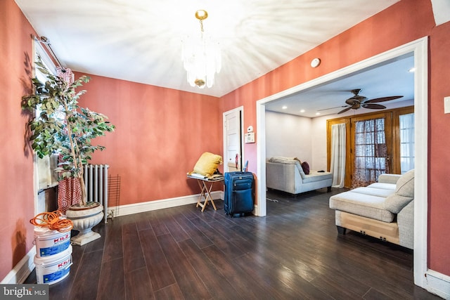 living area featuring wood-type flooring, ceiling fan with notable chandelier, and radiator heating unit