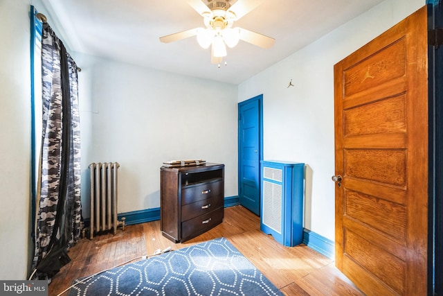 sitting room featuring wood-type flooring, radiator heating unit, and ceiling fan