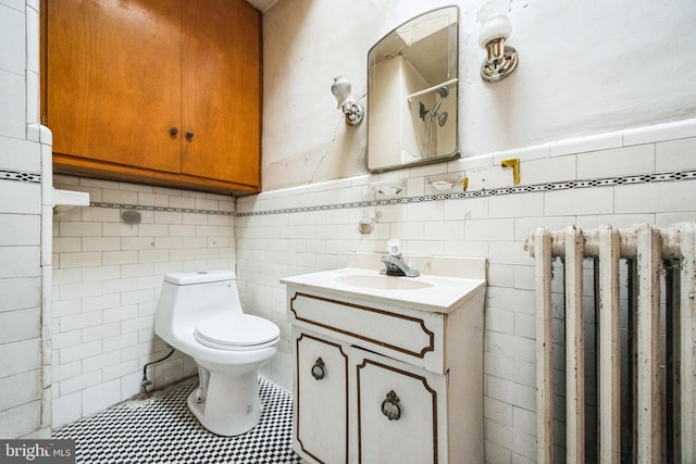 bathroom featuring radiator, tile walls, vanity, tile patterned floors, and toilet