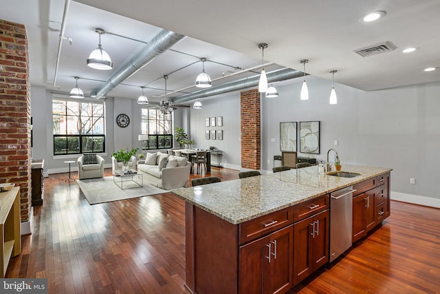 kitchen with pendant lighting, an island with sink, sink, stainless steel dishwasher, and light stone counters