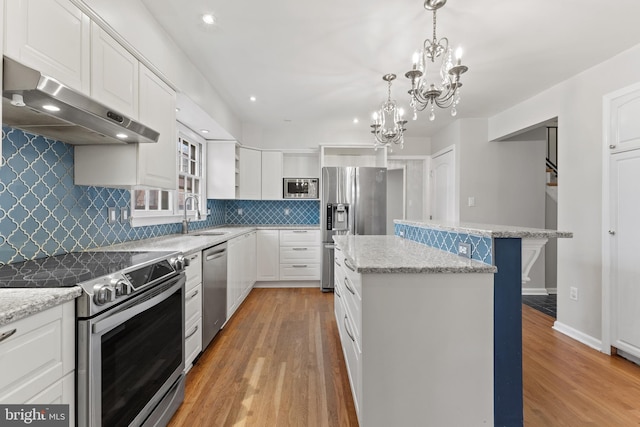 kitchen featuring a kitchen bar, a center island, pendant lighting, stainless steel appliances, and white cabinets