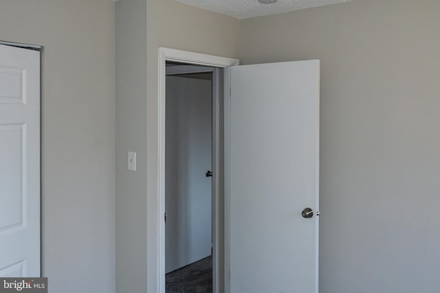 unfurnished bedroom with a closet, a textured ceiling, and carpet