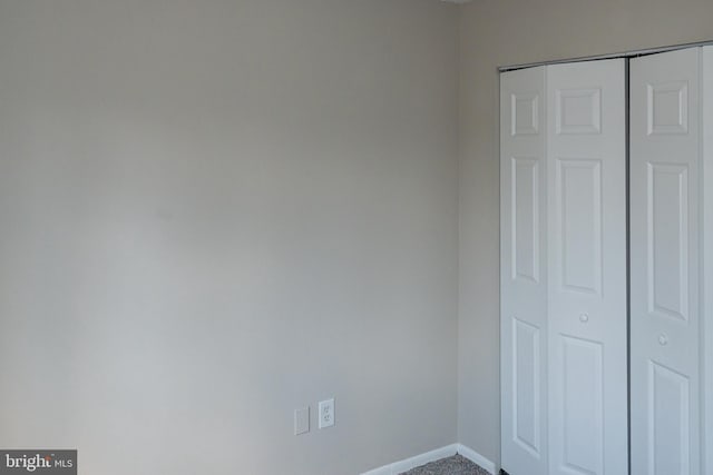 unfurnished bedroom featuring carpet, baseboards, and a closet