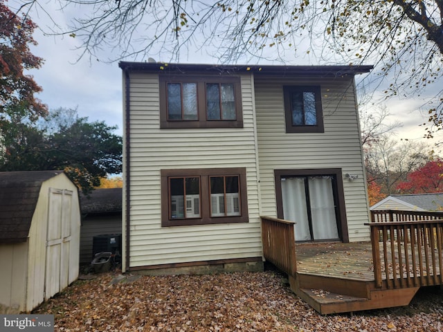 rear view of house with an outbuilding, cooling unit, a shed, and a wooden deck