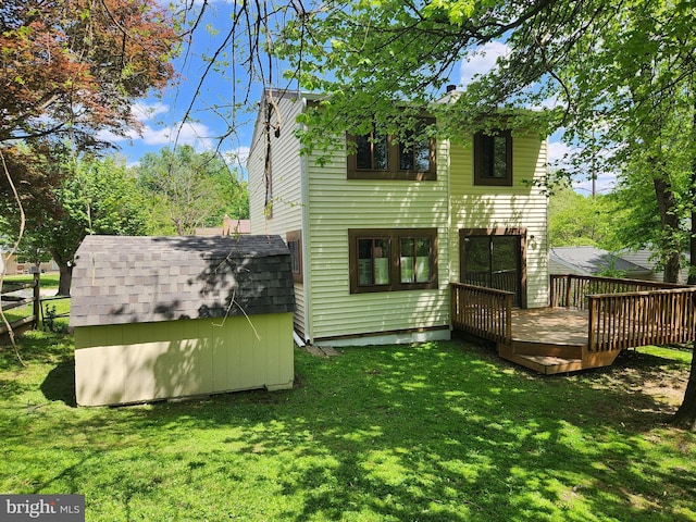 rear view of property featuring a lawn, a storage unit, an outbuilding, and a deck