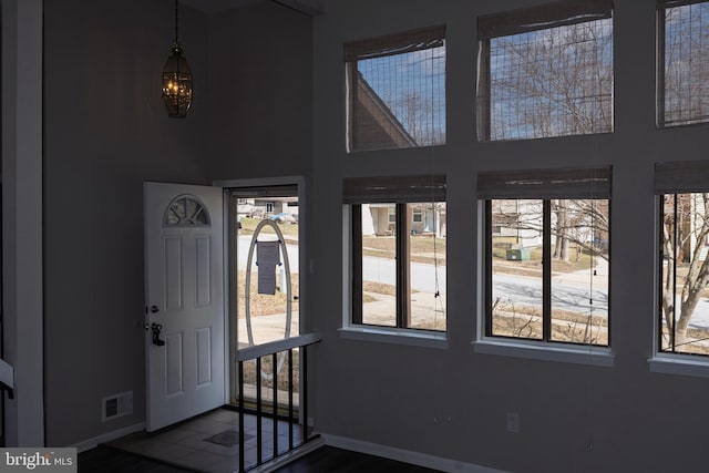 foyer entrance featuring a high ceiling, baseboards, and visible vents