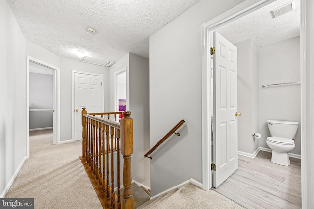 corridor featuring light colored carpet and a textured ceiling