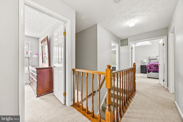 hall featuring light carpet and a textured ceiling