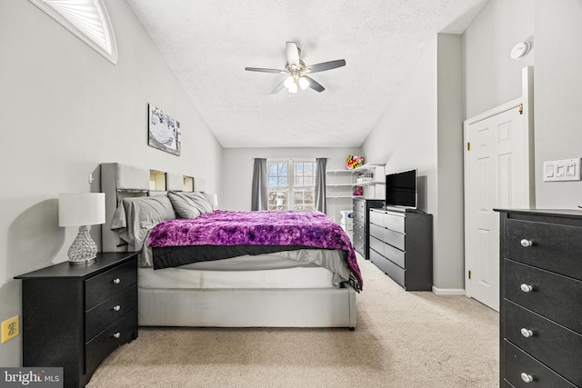 bedroom with ceiling fan, vaulted ceiling, light colored carpet, and a textured ceiling