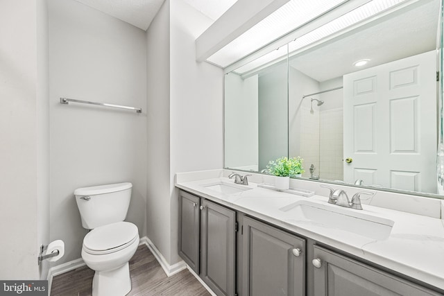 bathroom featuring vanity, toilet, hardwood / wood-style floors, and a tile shower