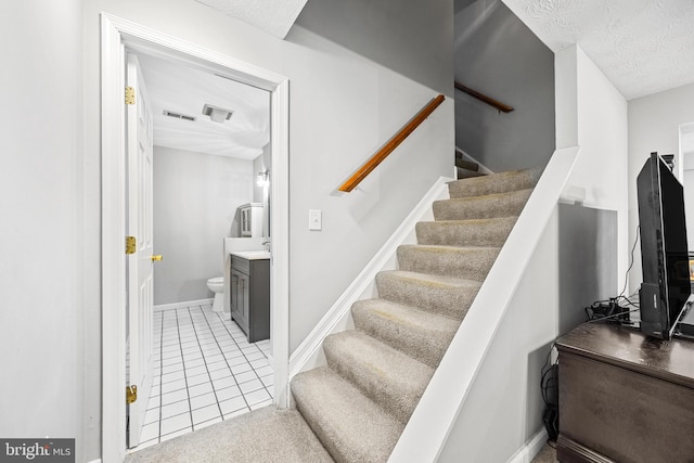 stairway featuring tile patterned flooring and a textured ceiling