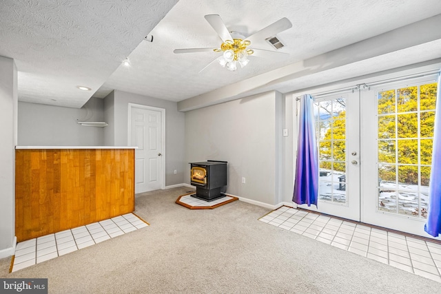 interior space with light carpet, french doors, a textured ceiling, and a wood stove