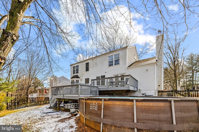 snow covered back of property with a deck