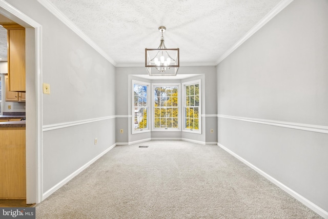 unfurnished dining area featuring ornamental molding, carpet, a textured ceiling, and a chandelier