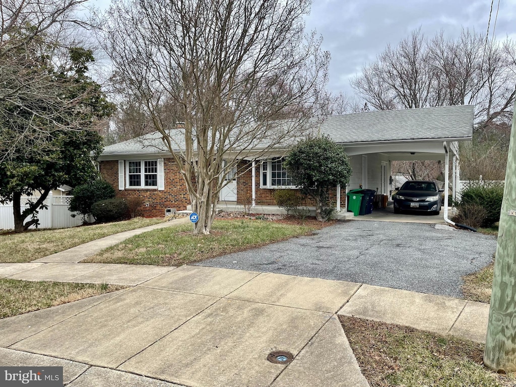 ranch-style house featuring aphalt driveway, an attached carport, roof with shingles, fence, and brick siding