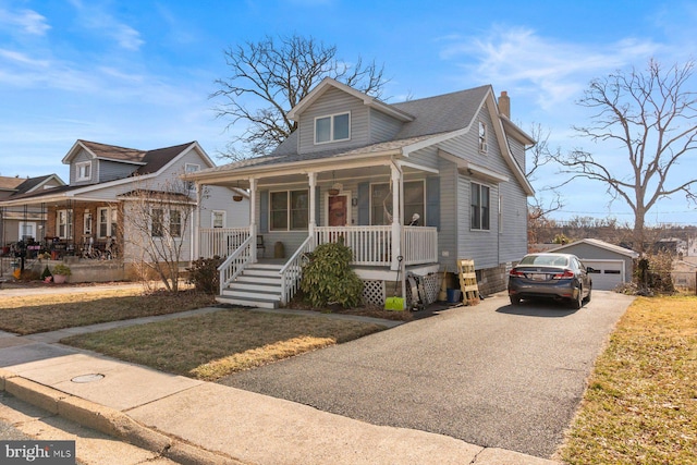 bungalow-style house featuring a garage, a shingled roof, a chimney, an outdoor structure, and a porch