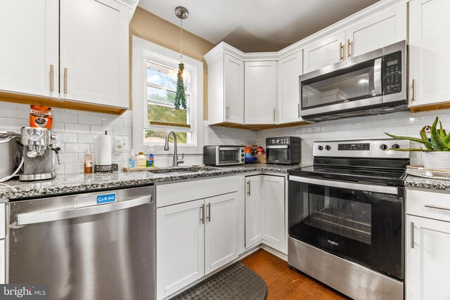 kitchen with dark wood-style floors, tasteful backsplash, appliances with stainless steel finishes, white cabinetry, and a sink