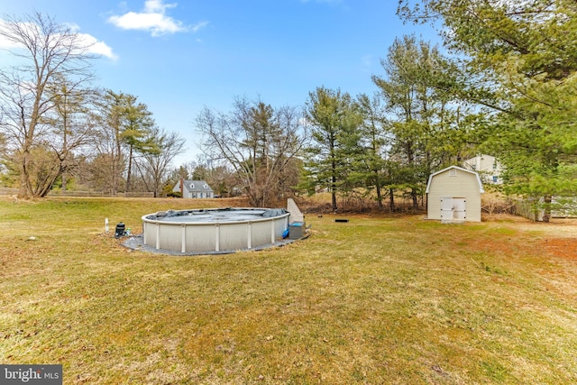 view of yard featuring a storage shed, a covered pool, and an outbuilding